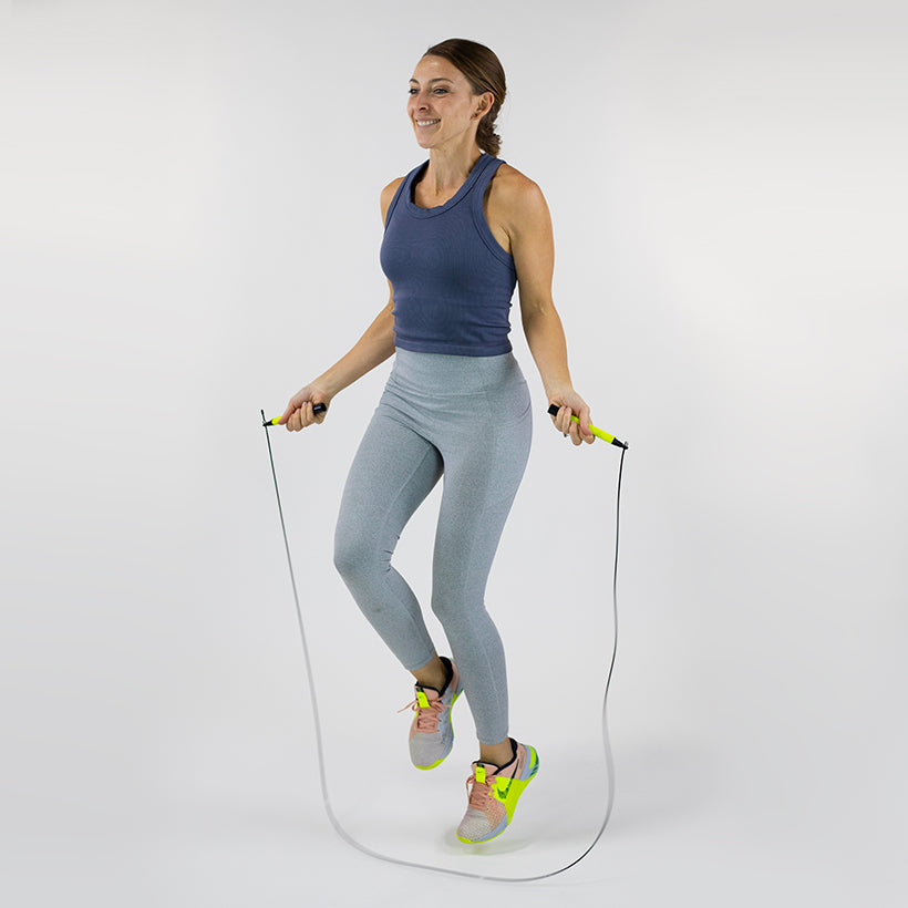 Woman jumping with a speed rope on a white background